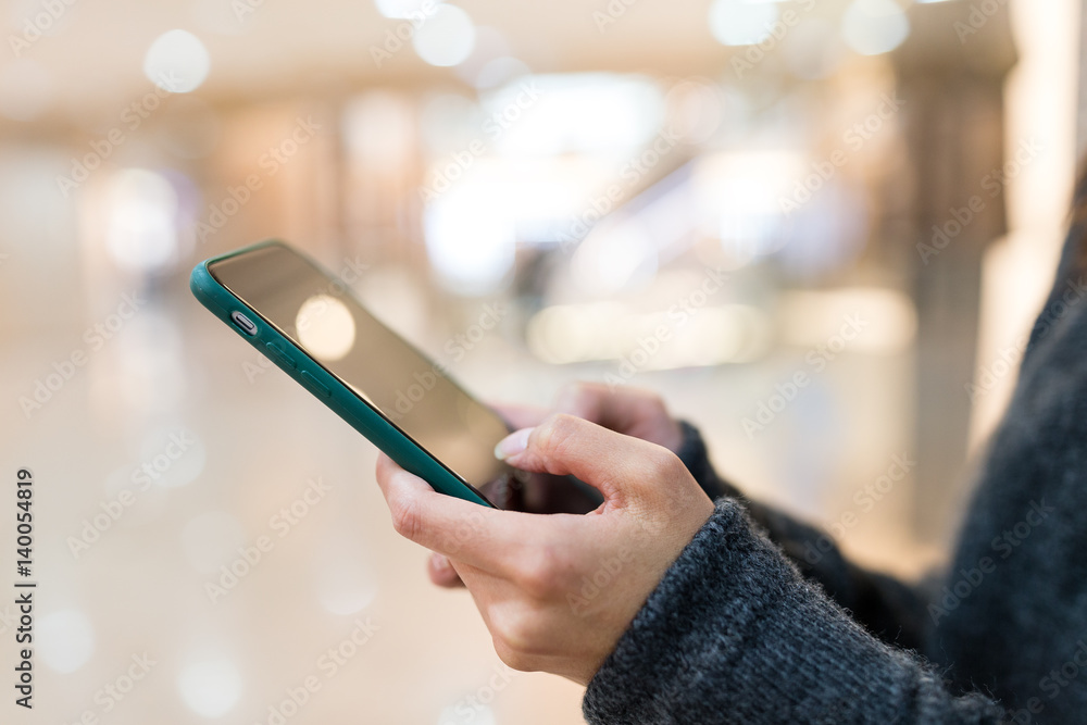 Woman sending sms on mobile phone in shopping mall Woman sending sms on mobile phone in shopping mall