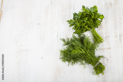 Parsley and dill on a light wooden background.