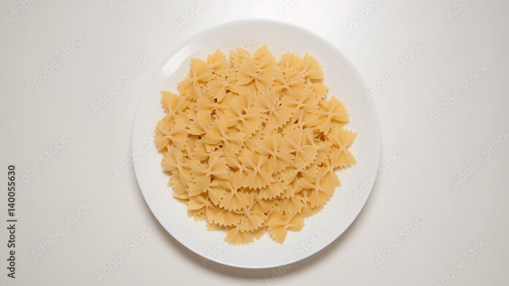 TOP VIEW: Bow noodles on a white dish on a white table TOP VIEW: Bow noodles on a white dish on a white table