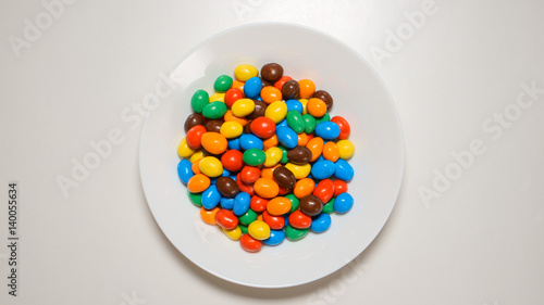 Bild auf Leinwand TOP VIEW: Colorful candies on a white dish on a white table