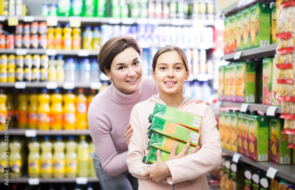 glad woman with daughter choosing refreshing beverages in supermarket