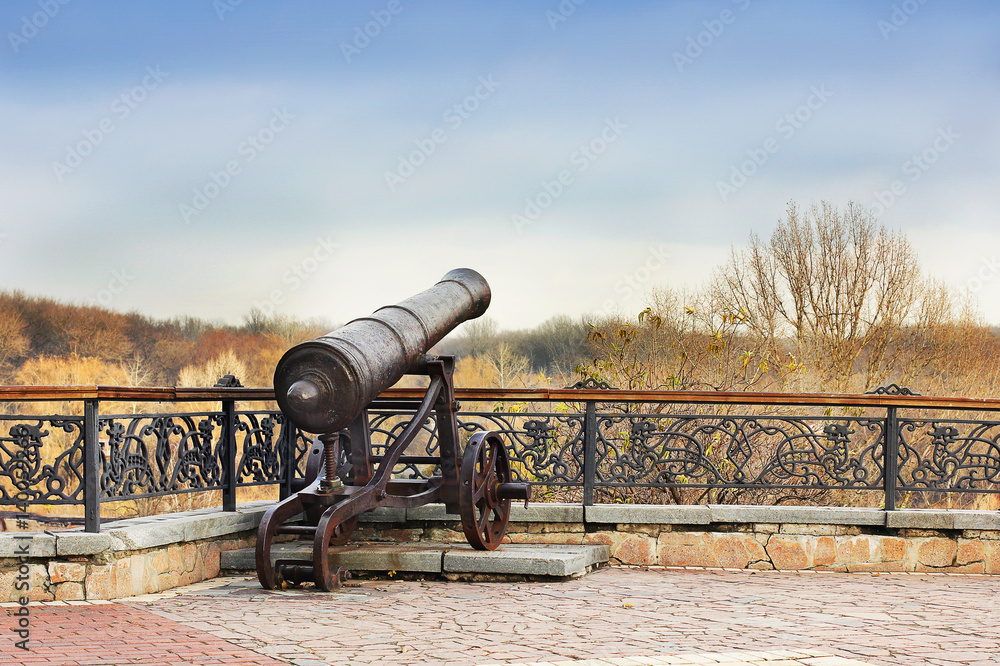 Black old cannon on hill. Military gun. Old cannon on the background of the city. Protecting the city. War. Protection. Weapon. Army Black old cannon on hill. Military gun. Old cannon on the background of the city. Protecting the city. War. Protection. Weapon. Army