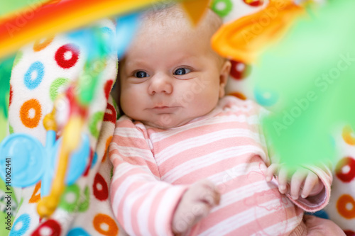 Cute adorable newborn baby playing on colorful toy gym