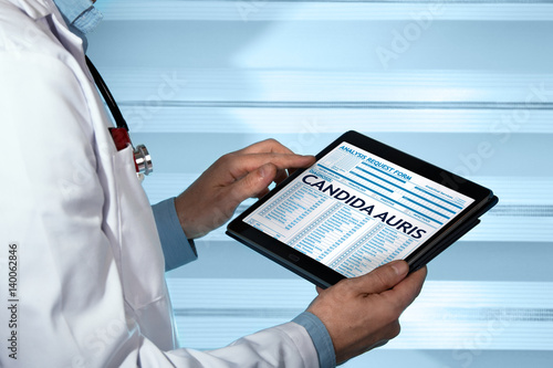 Photos doctor holding tablet with a candida auris diagnosis in digital medical report /