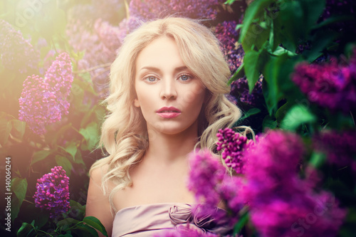 Romantic Woman with Summer Light and Lilac Flowers Outdoors. Young Beauty in Sunny Flowers Garden © artmim