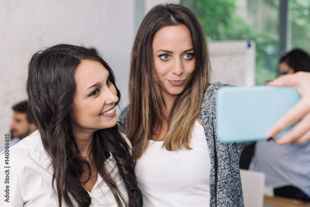 Two young female colleagues take selfie in the office during a break from business meeting Two young female colleagues take selfie in the office during a break from business meeting