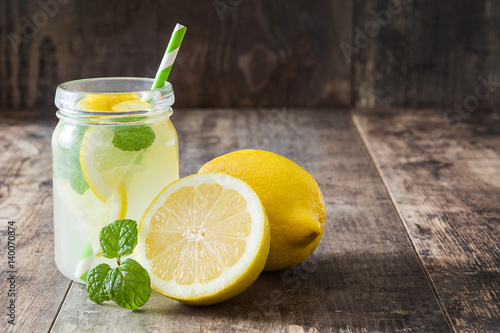 Fotografia Lemonade drink in a jar glass on wooden background. Copyspace.