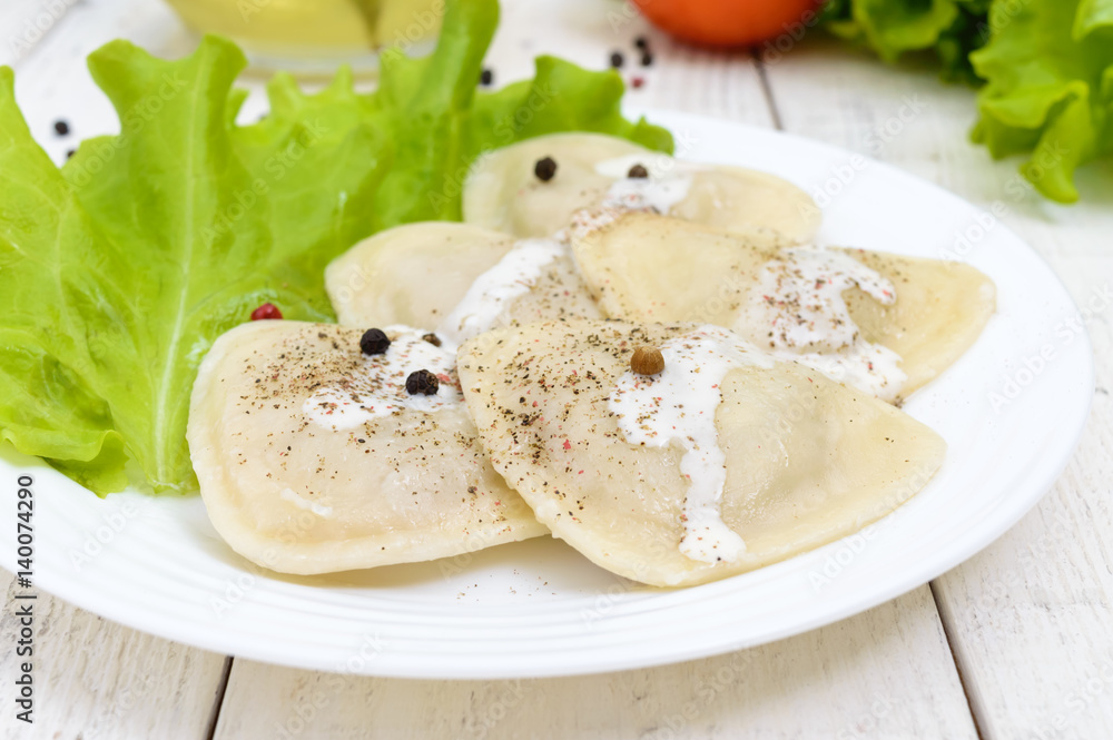 Italian ravioli (dumplings) in the shape of a heart on a plate on white wooden background. Italian ravioli (dumplings) in the shape of a heart on a plate on white wooden background.