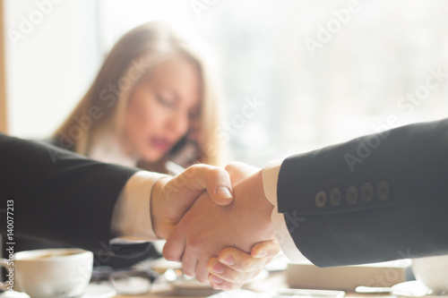 handshake business partners before signing the contract on the background of the workplace