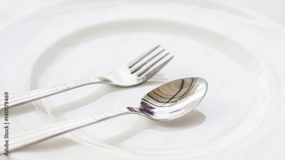 spoon and fork on a white plate. spoon and fork on a white plate.