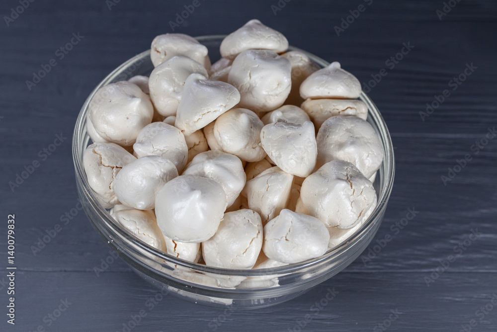 White mini meringue in transparent vase on a wooden background White mini meringue in transparent vase on a wooden background