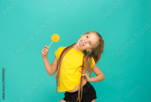 The teen girl with colorful lollipop on a blue background