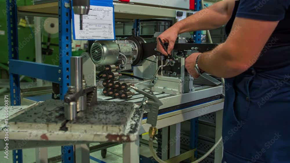 A man is taking an item from one machine to a different machine. Then the drill makes a hole in it.
A man is taking an item from one machine to a different machine. Then the drill makes a hole in it.
