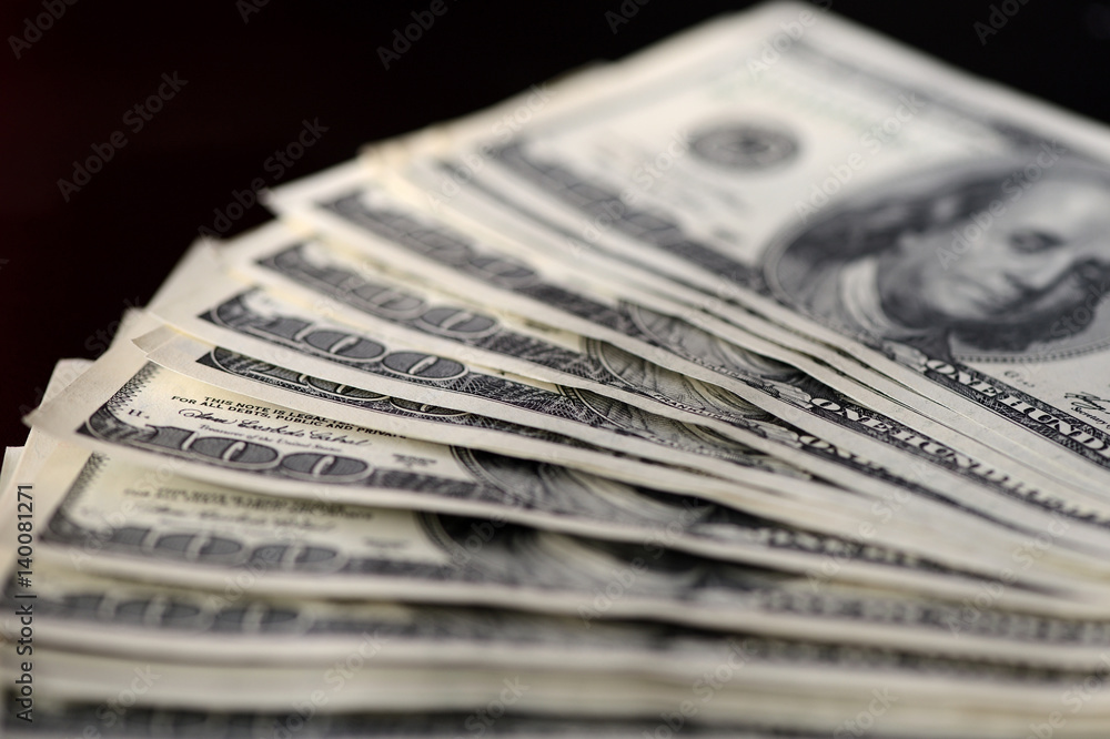 A pack of hundred dollar bills on a dark background A pack of hundred dollar bills on a dark background