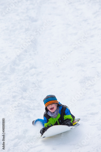 Boy riding a sled tobogganing in the snow