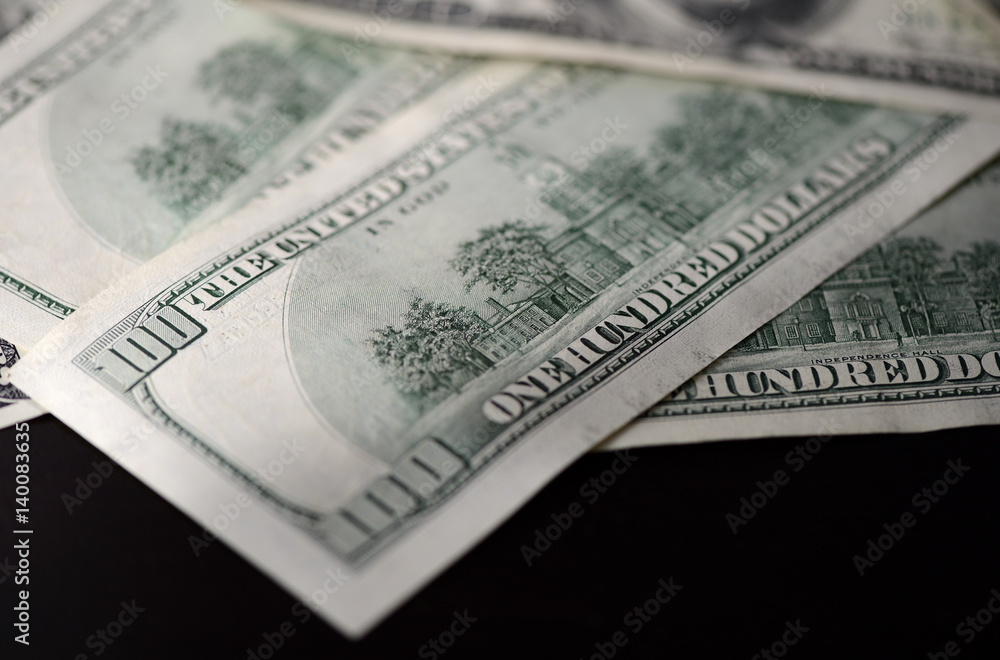 A pack of hundred dollar bills on a dark background A pack of hundred dollar bills on a dark background