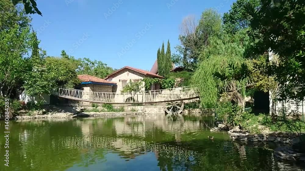 General view of natural park with green trees around a big lake and draw bridge, on bright sky background. General view of natural park with green trees around a big lake and draw bridge, on bright sky background.