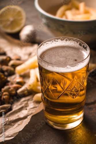 Glass of beer with blurred snack on the metal background