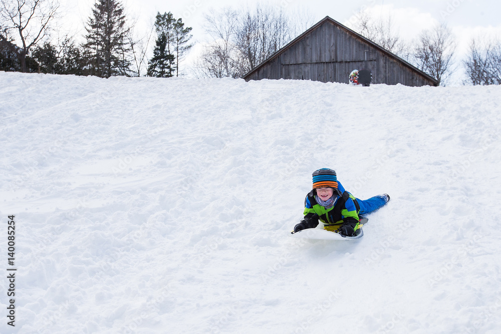 Boy riding a sled tobogganing in the snow