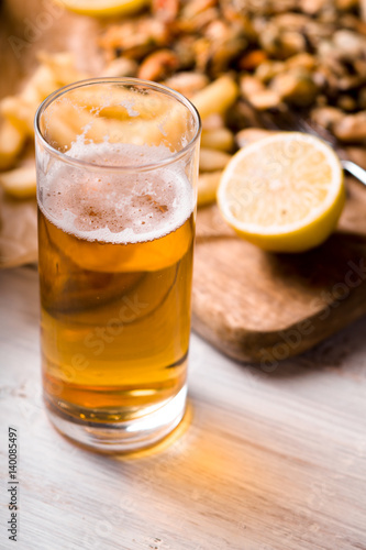 Glass of beer with blurred snack on the white wooden table