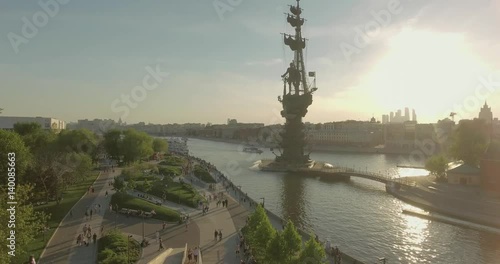 Aerial view of Peter the Great Statue on a spring day at sunset. Crowds of people walking along the park near river.