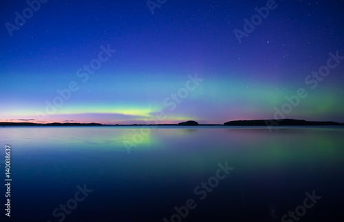 Northern lights dancing over calm lake 