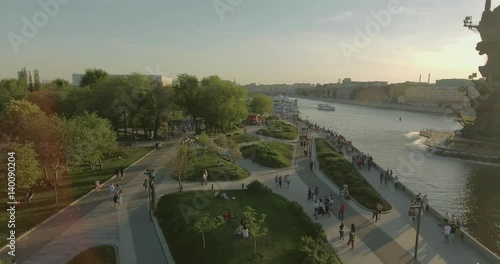 Aerial view of Peter the Great Statue on a spring day at sunset. Crowds of people walking along the park near river.