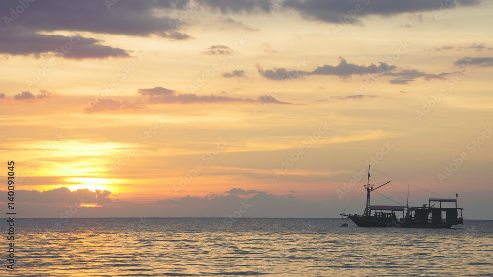 Boat silhouette crossing the ocean towards an orange sunset sky on the horizon, Labuan Bajo Bajawa.