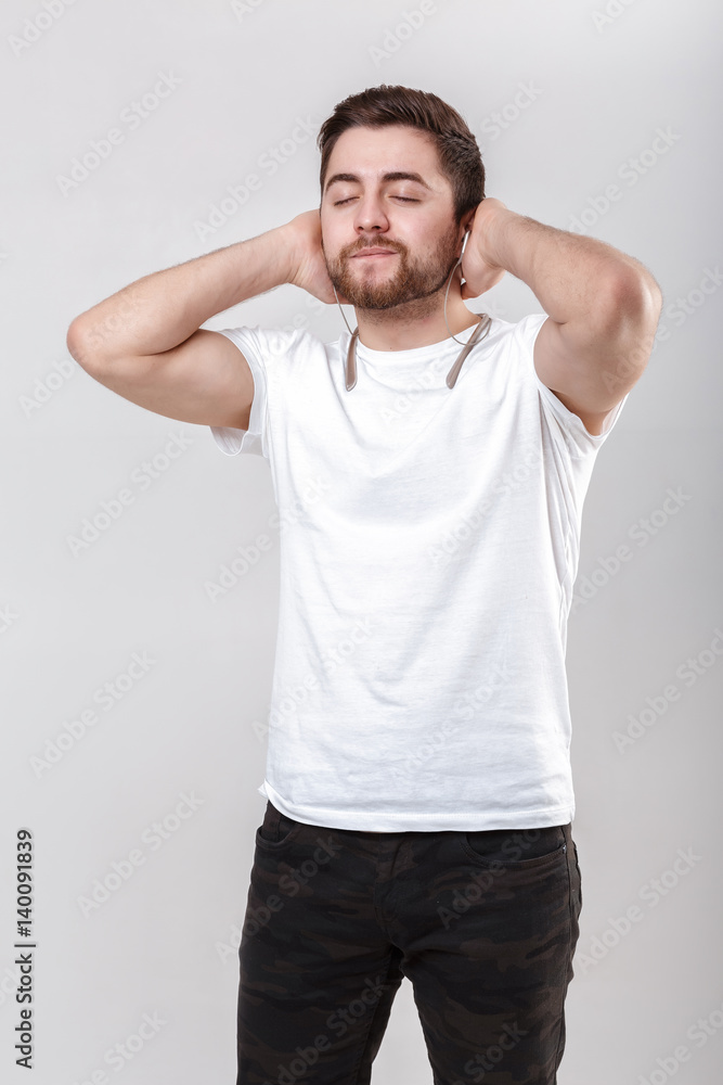 young handsome man with beard in t-shirt listening to music on headphones young handsome man with beard in t-shirt listening to music on headphones
