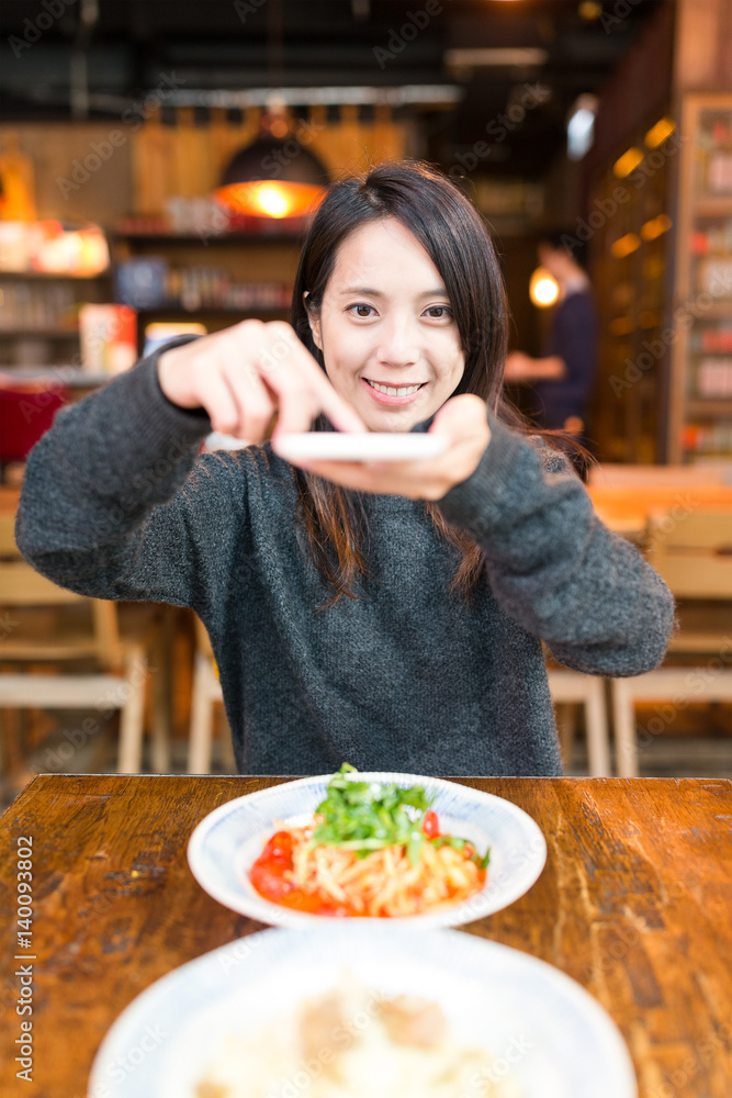Woman taking photo on her dishes in restaurant