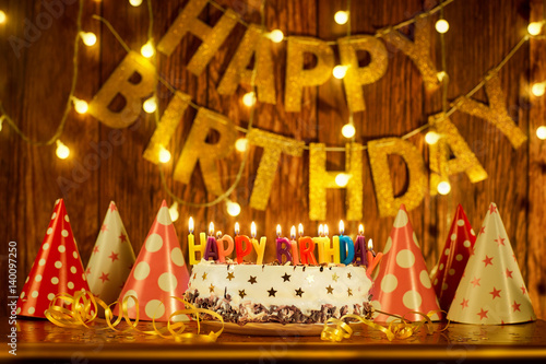 Canvas Print Happy birthday cake with candles on the background of garlands and letters