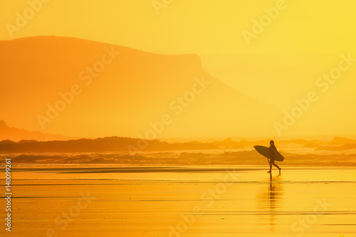 surfer in the beach at sunset