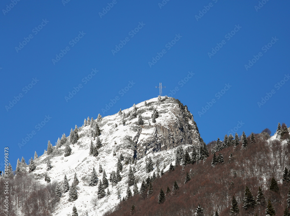 Fototapeta premium snow covered peak of the highest mountain with a cross on top