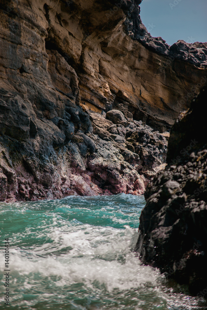 Indian ocean waves and rocks in the bay. Turquoise sea water with white foam meet rough stone rocks on the shore. Powerful and peaceful nature concept. Indian ocean waves and rocks in the bay. Turquoise sea water with white foam meet rough stone rocks on the shore. Powerful and peaceful nature concept.