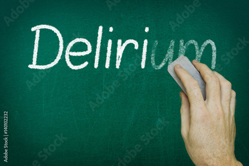 Hand erasing the word DELIRIUM written on blackboard