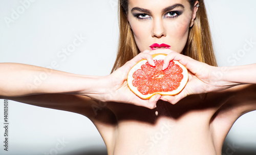 Pretty girl squeezing juice from fresh orange grapefruit