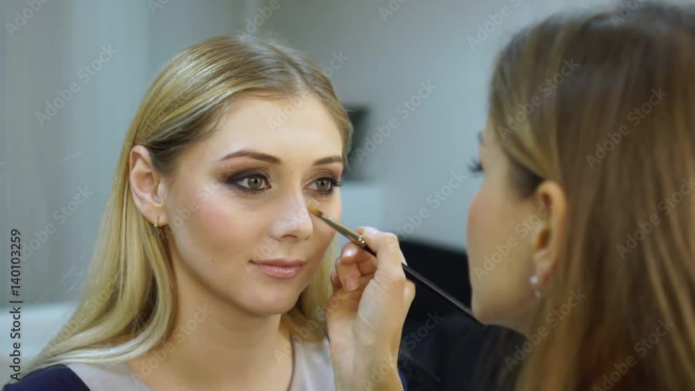 The makeup artist applies a concealer on area under eyes. The makeup artist applies a concealer on area under eyes.