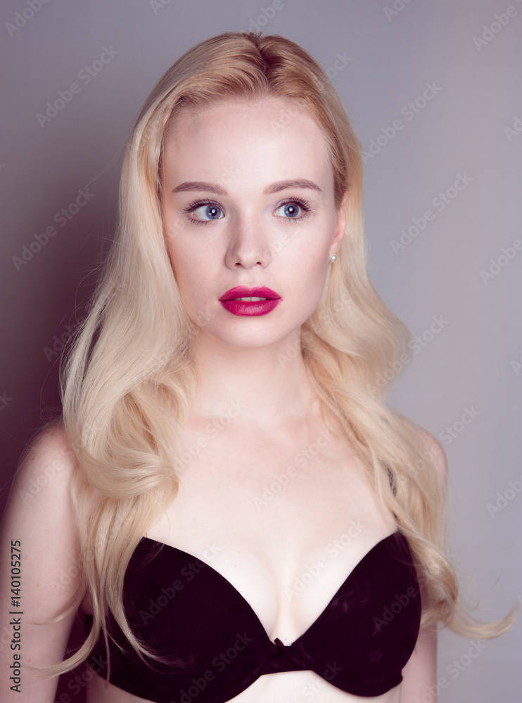 Beauty model girl with perfect make-up red lips and blue eyes looking at camera, wearing magenta bra. Portrait of attractive sexy young woman with blond hair. Beauty model girl with perfect make-up red lips and blue eyes looking at camera, wearing magenta bra. Portrait of attractive sexy young woman with blond hair.