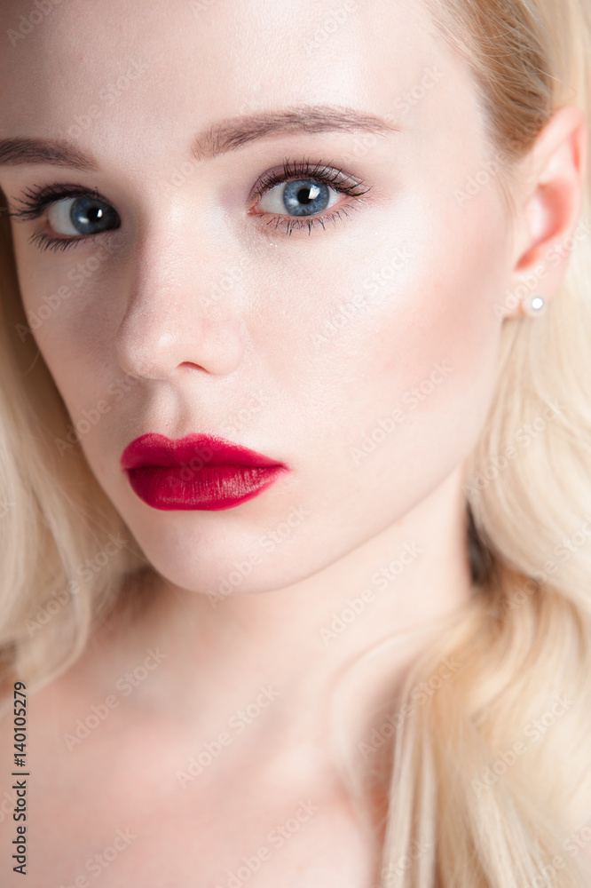 Beauty model girl with perfect make-up red lips and blue eyes looking at camera. Portrait of attractive young woman with blond hair. Beautiful female face with clear fresh skin. Fashion close up shot. Beauty model girl with perfect make-up red lips and blue eyes looking at camera. Portrait of attractive young woman with blond hair. Beautiful female face with clear fresh skin. Fashion close up shot.