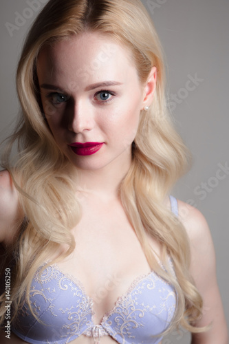 Beauty model girl with perfect make-up red lips and blue eyes looking at camera, wearing blue bra. Portrait of attractive sexy young woman with blond hair. 