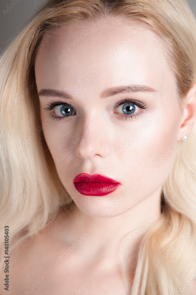 Beauty model girl with perfect make-up red lips and blue eyes looking at camera. Portrait of attractive young woman with blond hair. Beautiful female face with clear fresh skin. Fashion close up shot. Beauty model girl with perfect make-up red lips and blue eyes looking at camera. Portrait of attractive young woman with blond hair. Beautiful female face with clear fresh skin. Fashion close up shot.