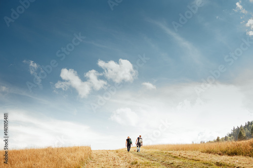 Two mans walk on golden field under blue sky © Soloviova Liudmyla