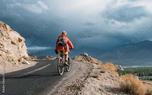 Bike tourist rides on Himalaya mountain road on way to buddist monastery