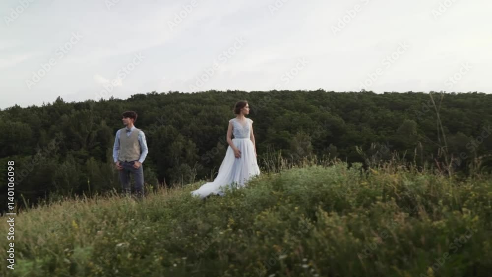 Romantic and happy caucasian couple in stylish clothes standing on the background of beautiful nature. Love, relationships, romance, happiness concept. Man and woman walking outdoors together. Romantic and happy caucasian couple in stylish clothes standing on the background of beautiful nature. Love, relationships, romance, happiness concept. Man and woman walking outdoors together.