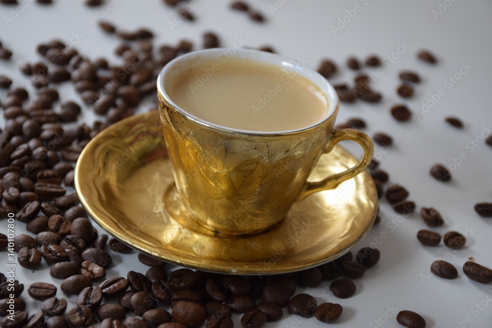 Goldene Tasse mit Kaffee und Kaffeebohnen Stock-Foto | Adobe Stock