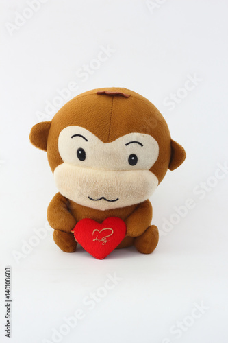 Stuffed brown monkey holding a red heart on a white background.