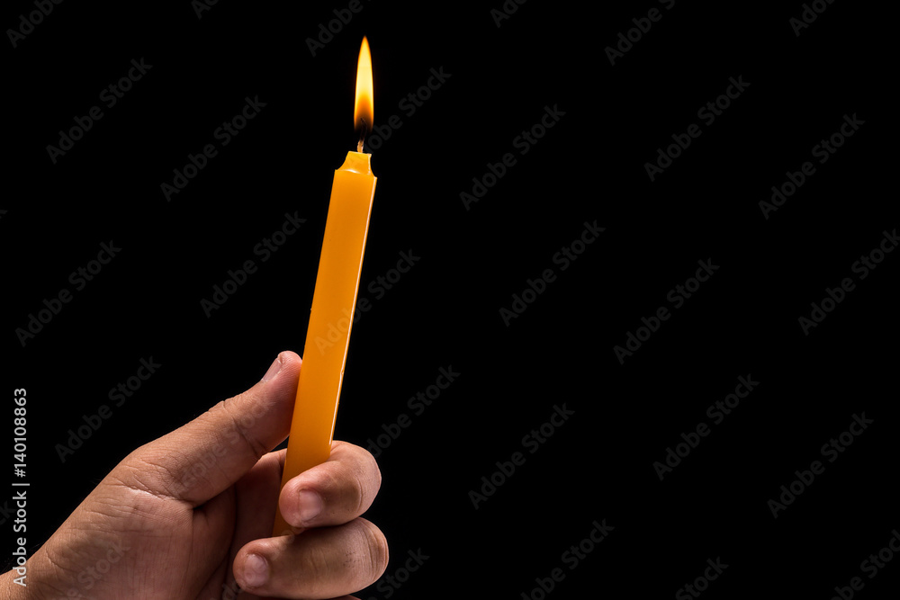 Hand holding light burning candle. Studio shot isolated on black background Hand holding light burning candle. Studio shot isolated on black background