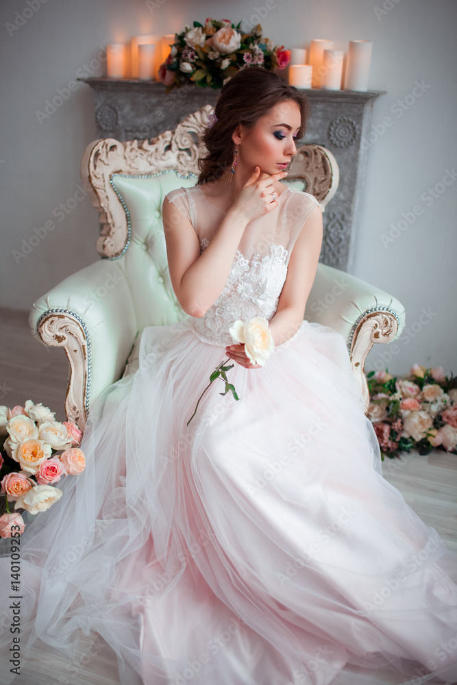 Pretty young bride in pink wedding dress sitting on a luxurious chair.