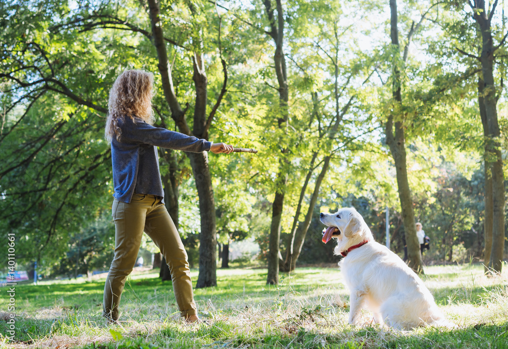 Obraz premium Young female playing with labrador retriever dog in park