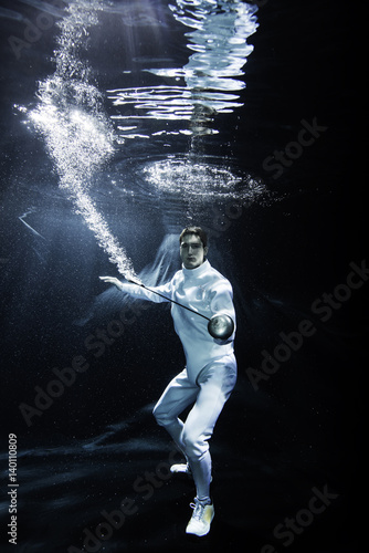a male fencer fighting underwater with an epee